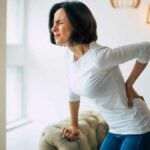 Chronic lower back pain. Adult woman is holding her lower back