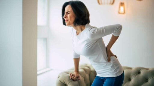 Chronic lower back pain. Adult woman is holding her lower back