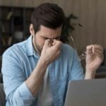 Exhausted man suffer from dizziness working on laptop
