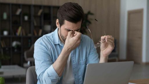 Exhausted man suffer from dizziness working on laptop