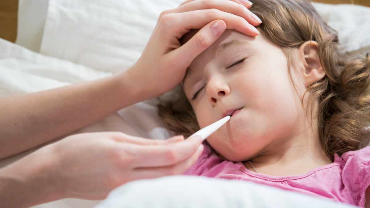 bambina a letto che si misura la febbre