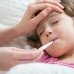 girl in bed measuring fever