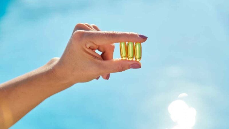 mano mostra tre pillole di vitamina D B12