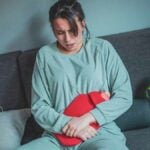 donna cura gli spasmi con borsa di acqua calda