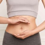 donna mima l'atto di sostenere qualcosa di fronte alla pancia