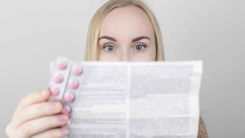 Ragazza che legge bugiardino del farmaco per prevenire effetti collaterali