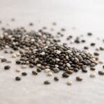 Semi-processed chia seeds are artistically arranged on a smooth, light-toned surface.
