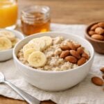 Rappresentazione di ingredienti per una colazione semplice, come avena, banane e mandorle su un tavolo neutro.